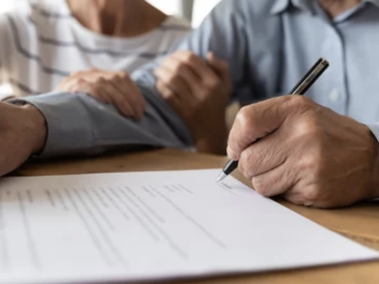 Man signing a document with black pen